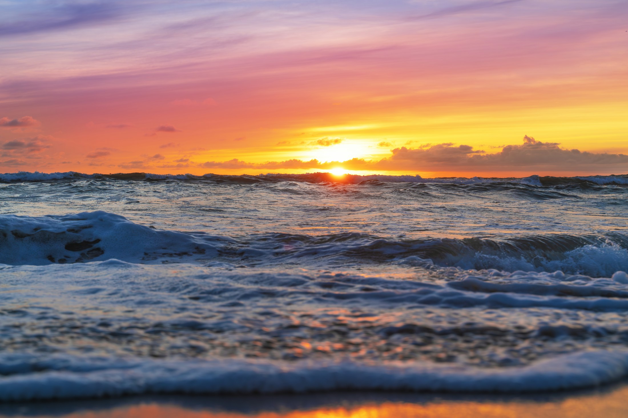Pacific Ocean waves beneath a glowing evening sky
